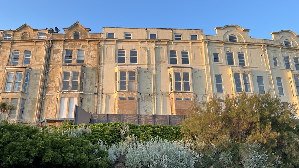 a large building with many windows and bushes in front of it