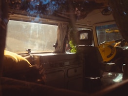 A sunlit van interior with colorful textiles and travel essentials neatly arranged.