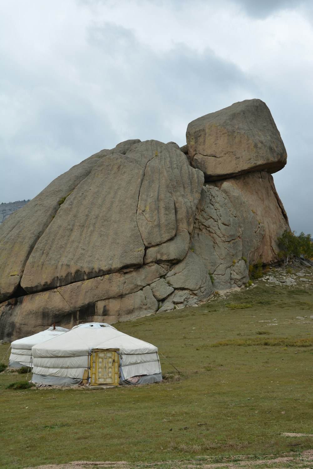 a large rock formation with a yurt in the foreground
