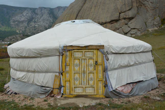 a yurt in the mountains with a yellow door