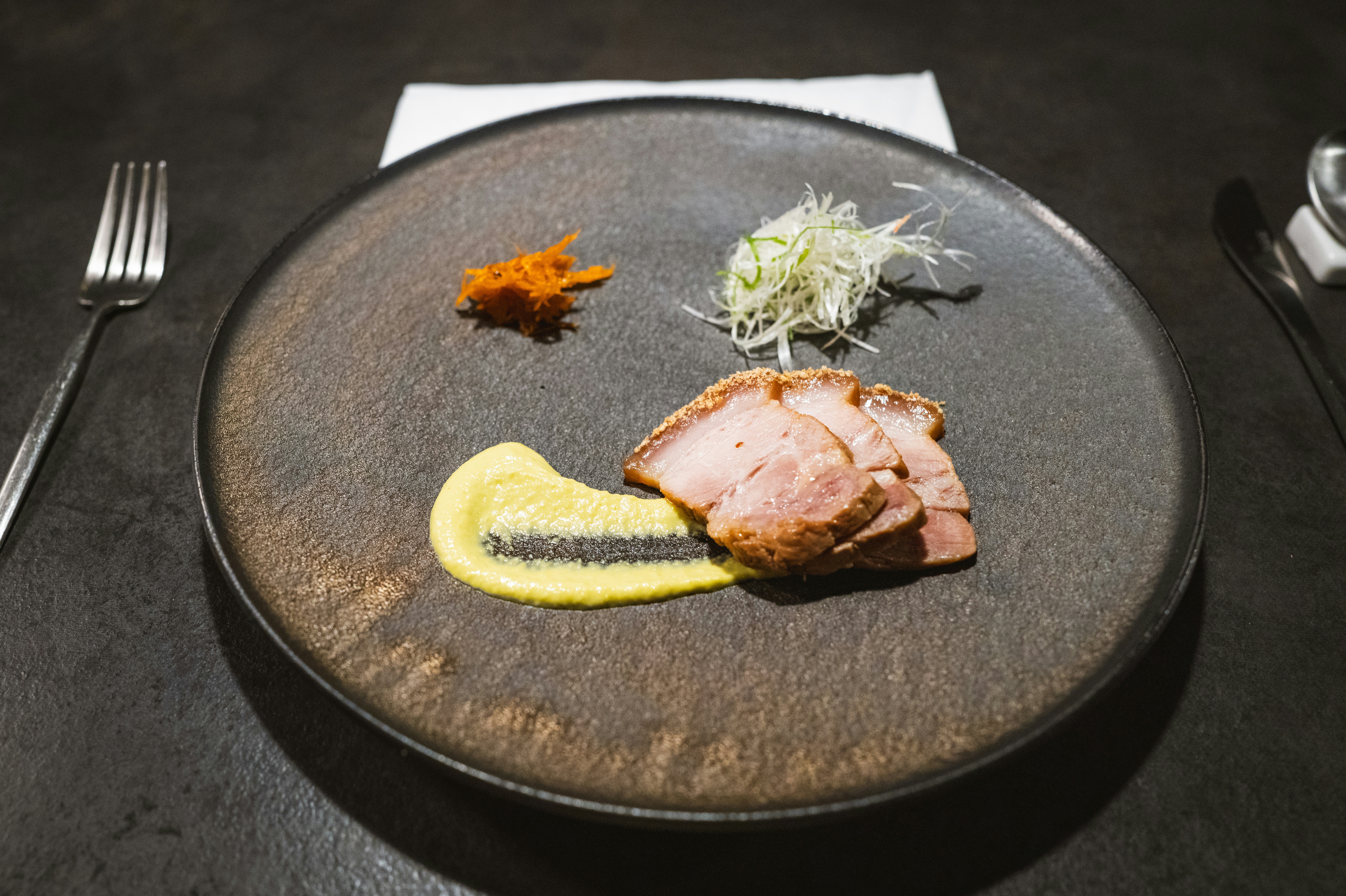 a black plate topped with meat and vegetables, 