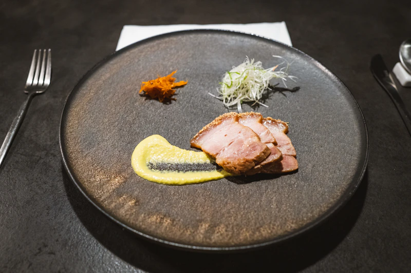 a black plate topped with meat and vegetables