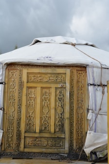 a yurt with a wooden door and a tarp over it