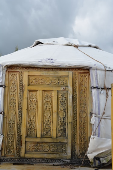 a yurt with a wooden door and a tarp over it