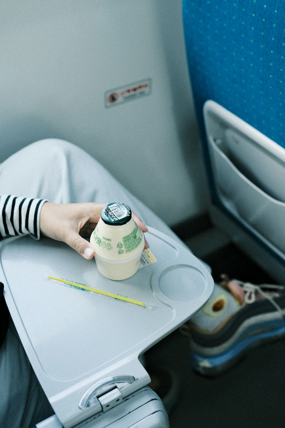 a person sitting on a plane holding a cup of coffee