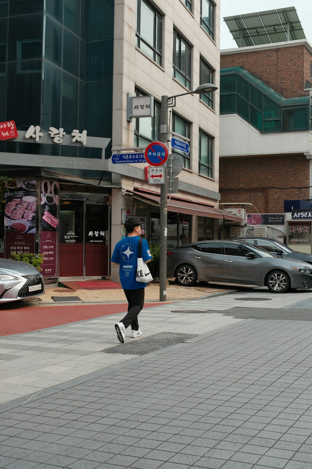 a man walking down a street next to tall buildings