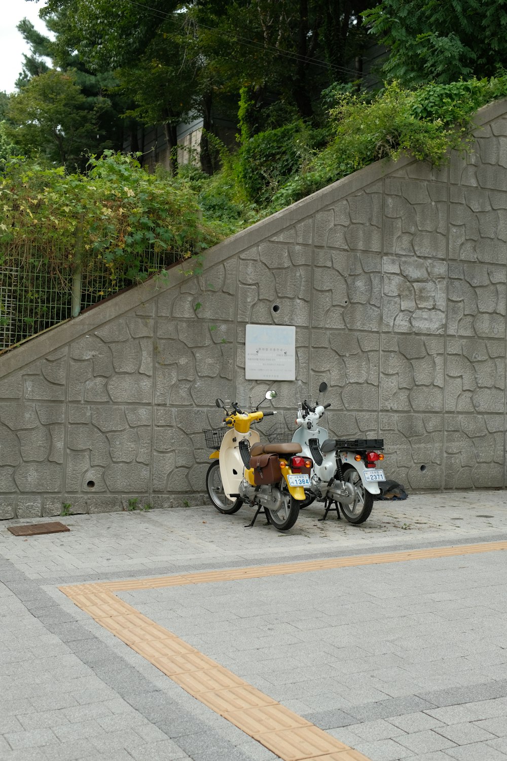 a couple of scooters parked next to a stone wall