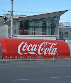 a large coca - cola truck is parked on the side of the road