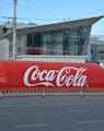 a large coca - cola truck is parked on the side of the road