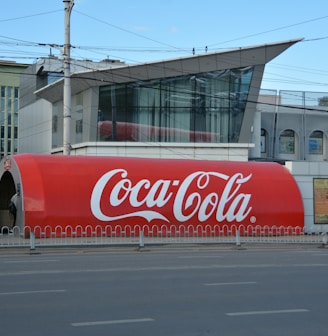 a large coca - cola truck is parked on the side of the road