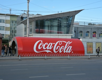 a large coca - cola truck is parked on the side of the road