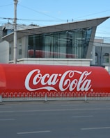 a large coca - cola truck is parked on the side of the road