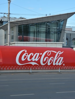 a large coca - cola truck is parked on the side of the road