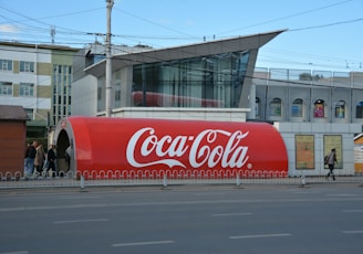 a large coca - cola truck is parked on the side of the road