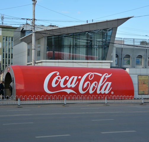 a large coca - cola truck is parked on the side of the road