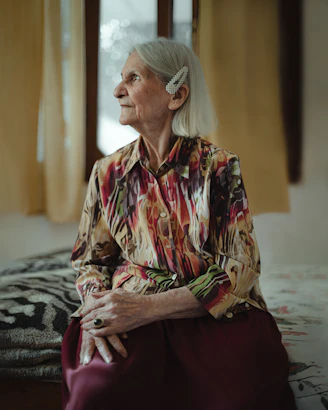 A caregiver assisting a senior with grooming and dressing in a bright, comfortable bedroom.
