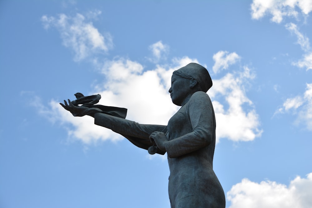 eine Statue einer Frau, die ein Paar Handschuhe hält