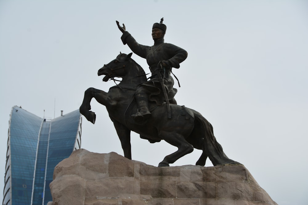 uma estátua de um homem montado em um cavalo ao lado de um edifício alto