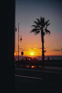 A peaceful scene of a driver holding a steering wheel with a sunset over the ocean in the background.