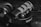 A black and white close-up of audio equipment featuring a microphone and headphones. The Rode microphone with a metal mesh is positioned prominently on top of Audio-Technica headphones. A keyboard can be seen blurred in the background, adding context to a studio or recording setup.