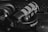 A black and white close-up of audio equipment featuring a microphone and headphones. The Rode microphone with a metal mesh is positioned prominently on top of Audio-Technica headphones. A keyboard can be seen blurred in the background, adding context to a studio or recording setup.