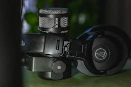 Close-up of a microphone and headphones resting on a soundproof booth table.