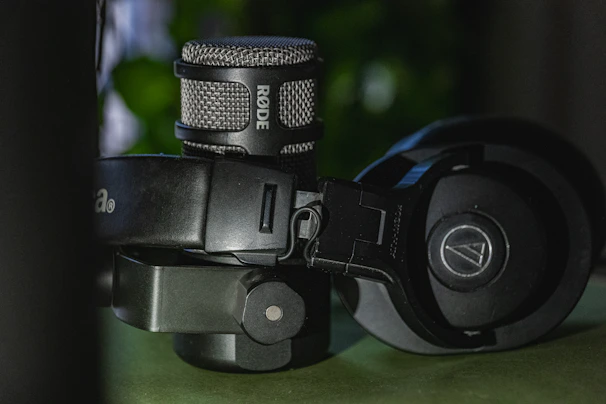 Close-up of professional headphones and microphones arranged on a wooden table.