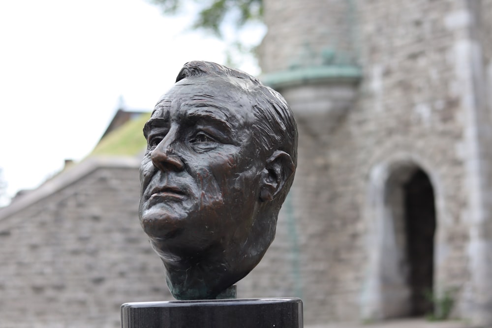 a statue of a man's head in front of a castle