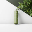 Smooth lotion bottles and tubes surrounded by fresh green leaves.