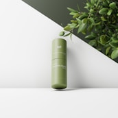 Minimalist product display featuring Klean Cosmetics skincare bottles with green leaves around.