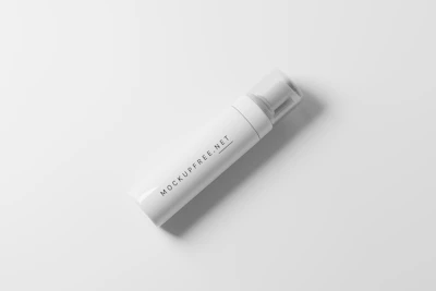 A white, cylindrical foam dispenser bottle is placed against a smooth, light gray background. The bottle features simple black text that reads 'MOCKUPFREE.NET' along its body. It has a clear plastic cap.