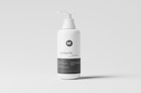 A white plastic pump bottle labeled as a cosmetic mockup stands against a neutral gray background. The bottle features a minimalist design with the text 'cosmetic mockup' printed in black. The pump dispenser is white, matching the bottle's color.