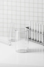Minimalist lab setup with glass beakers and natural ingredients arranged on a clean white surface.
