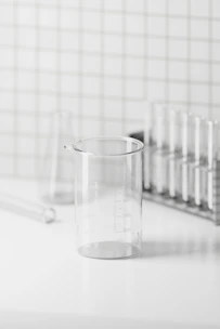 Minimalist lab setup with glass beakers and natural ingredients arranged on a clean white surface.