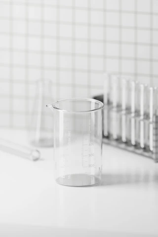 Close-up of clear borosilicate glass beakers and flasks arranged neatly on a laboratory bench.
