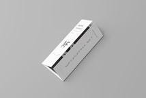 A white tri-fold pamphlet with a minimalist design placed on a light gray background. The pamphlet features bold, black typography with the letters 'MF' prominently displayed. The text 'MOCKUPFREE.NET' is visible, along with some smaller text details. The pamphlet appears sleek and professional.