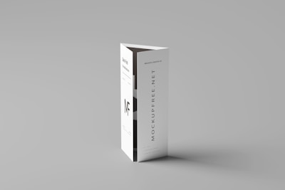 A folded paper brochure with a minimalist design is placed upright against a neutral background. The brochure has text elements, including a bold 'MF' logo and vertical text 'MOCKUPFREE.NET.'