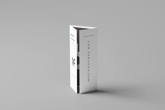A folded paper brochure with a minimalist design is placed upright against a neutral background. The brochure has text elements, including a bold 'MF' logo and vertical text 'MOCKUPFREE.NET.'