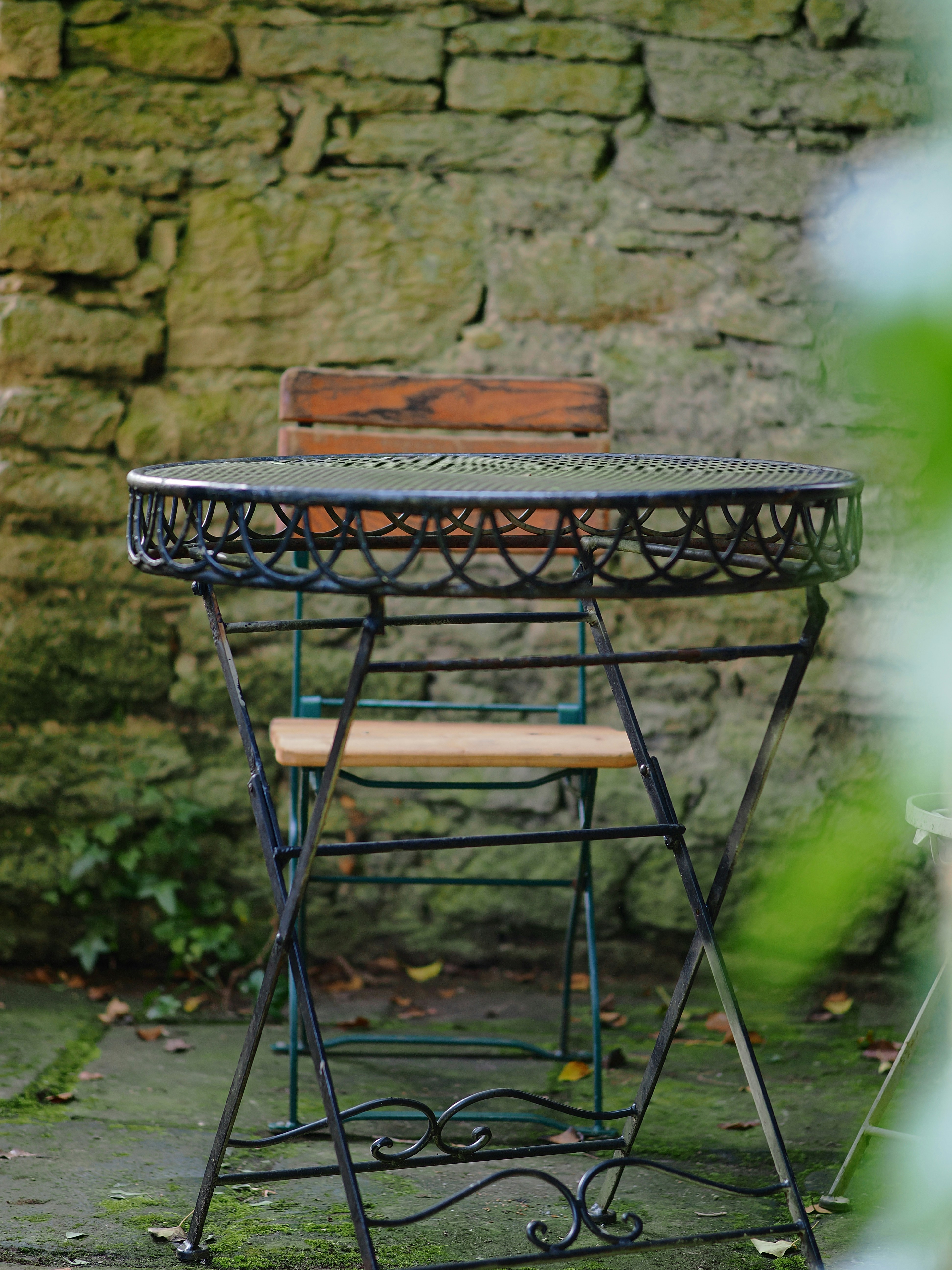 a table and chair sitting in front of a stone wall