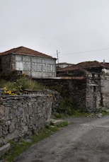 a stone wall with a building in the background