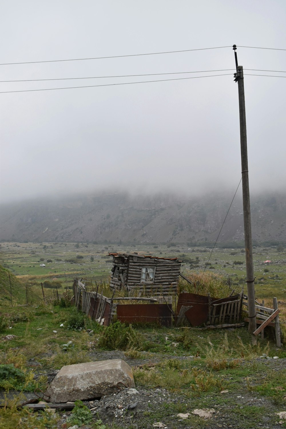 a wooden shack sitting on top of a lush green field