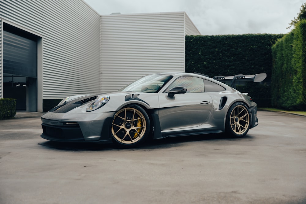 a grey sports car parked in front of a building