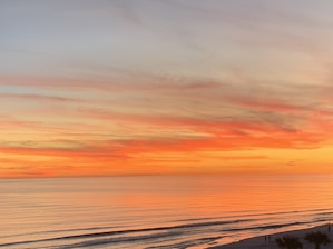 A vibrant sunset over a tranquil beach with silhouettes of travelers enjoying the view.