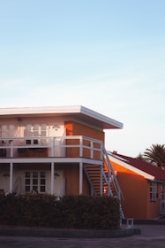 an orange building with a white balcony and stairs