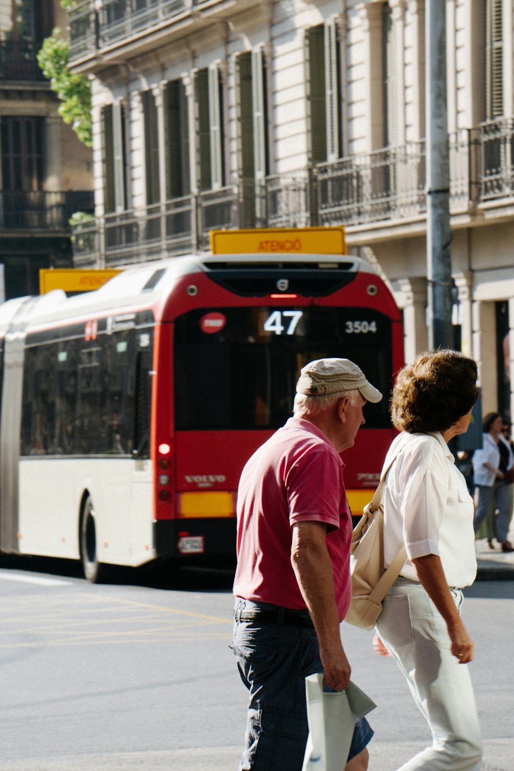 a man and woman crossing the street in front of a bus