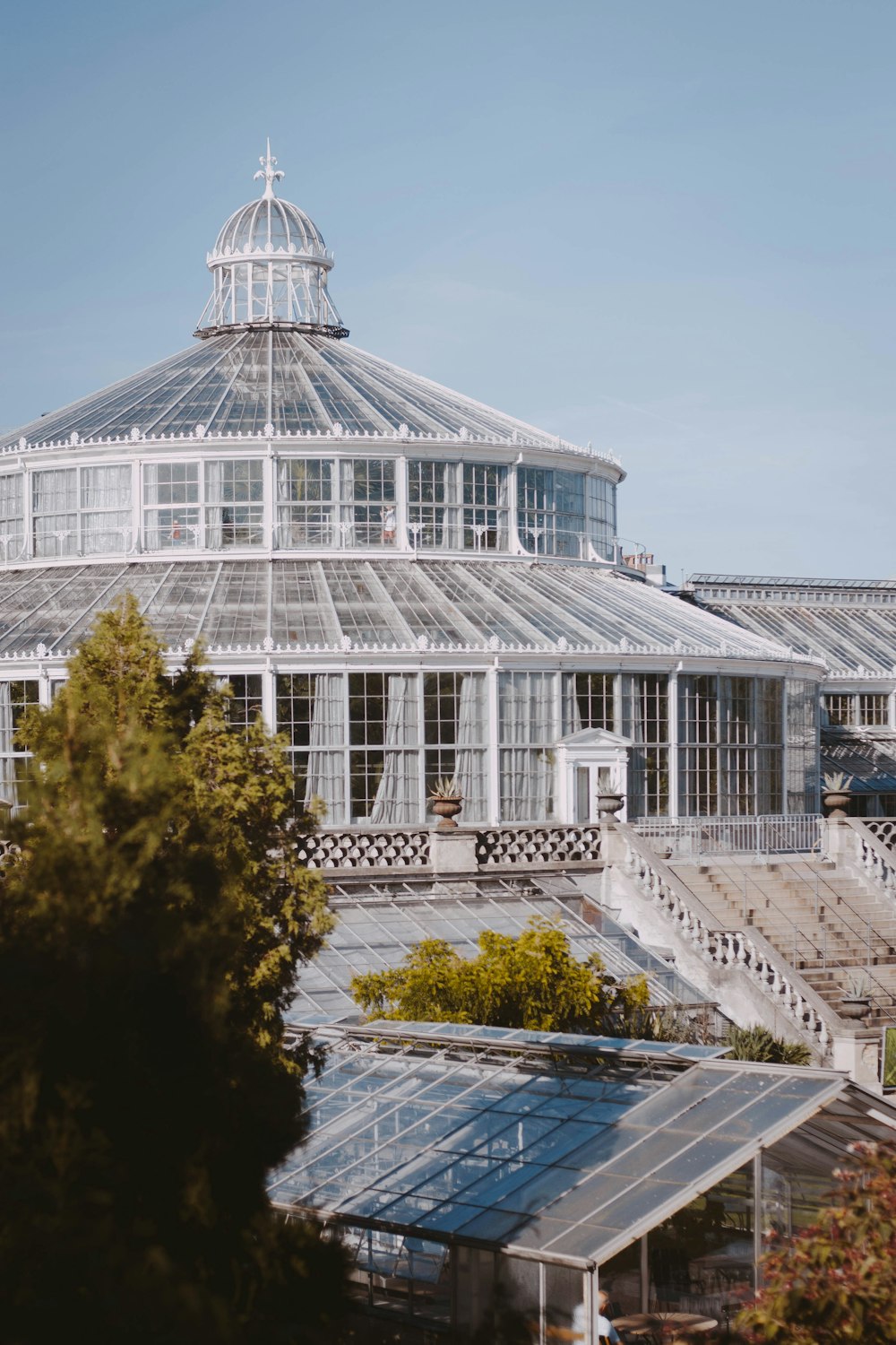 a large building with a glass roof in the middle of a park