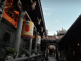 The temple’s intricate wood carvings illuminated by soft lantern light at dusk.