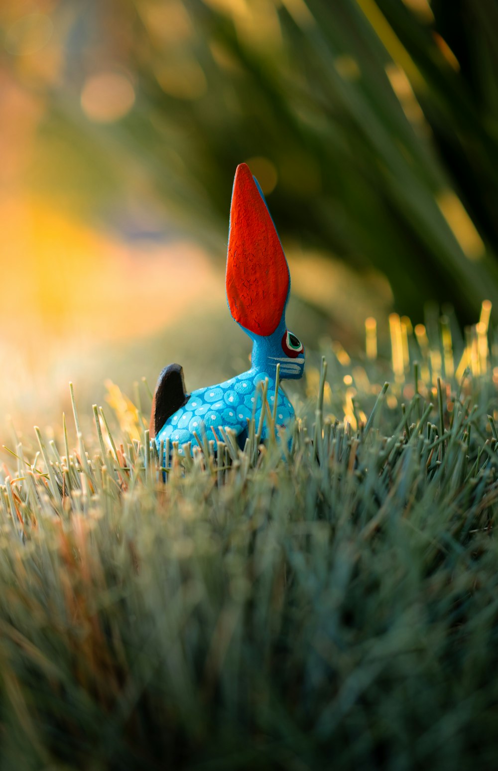 a blue toy with a red hat laying in the grass