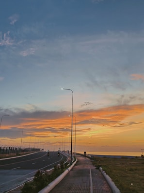 A group of tourists riding bikes along a coastal road near Dona Paula at sunset