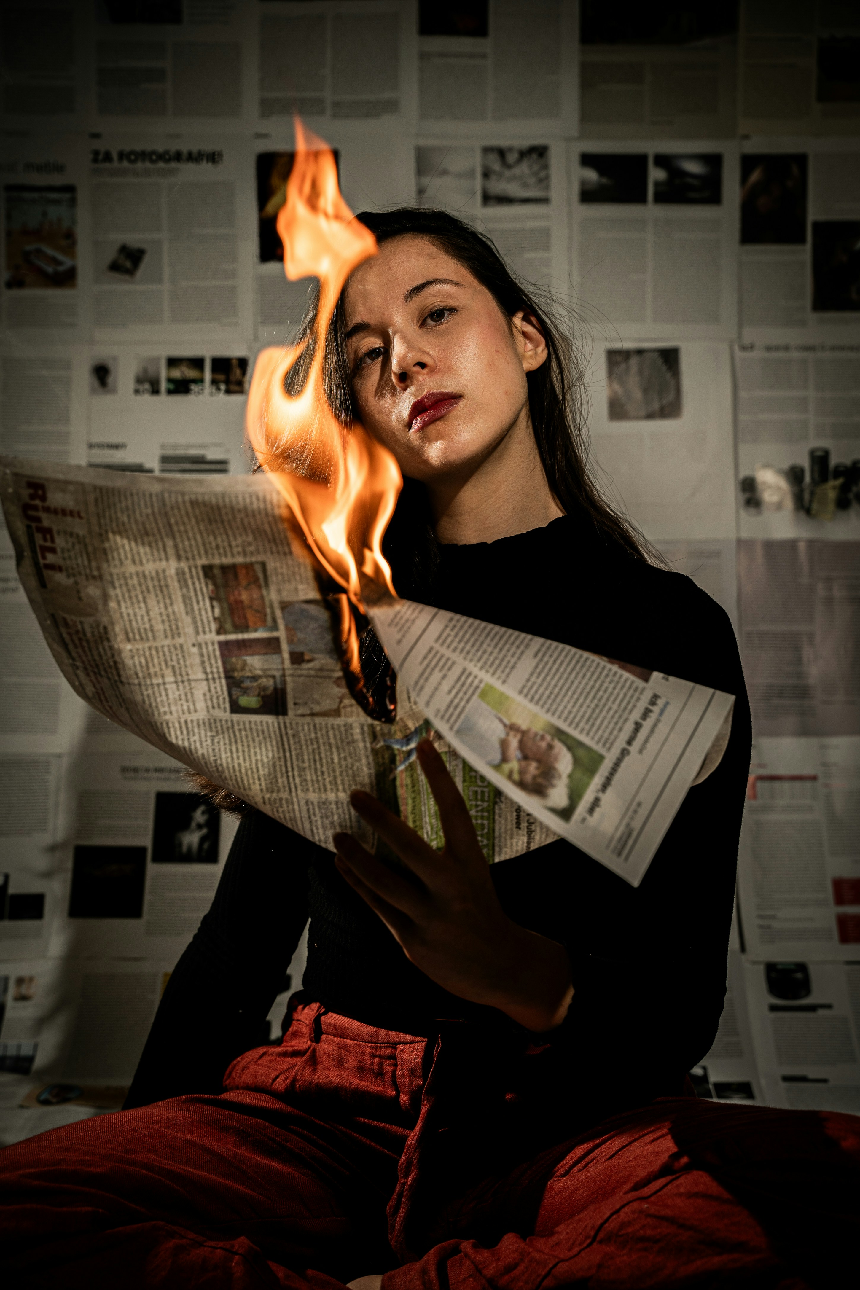 a woman sitting on a bed while holding a newspaper